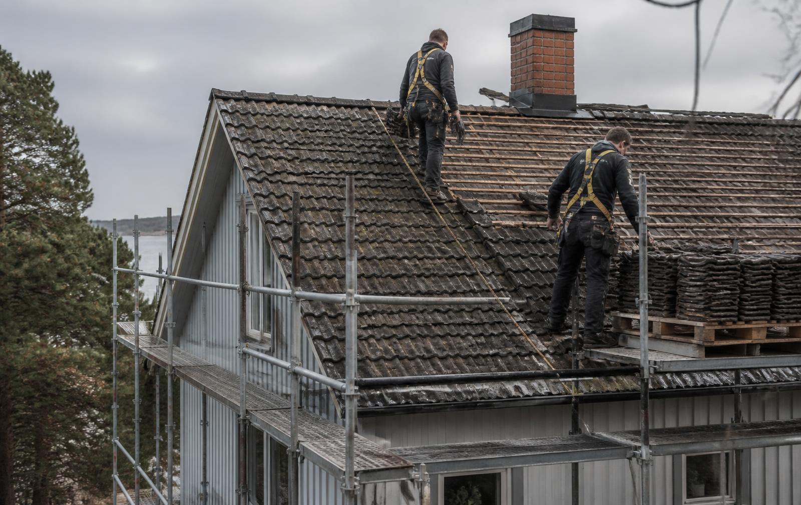 Takläggare byter takpannor på ett hus i Göteborg